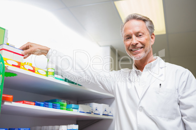 Senior pharmacist taking medicine from shelf