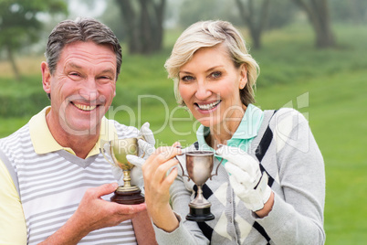 Happy golfing couple with trophy