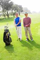 Golfing friends smiling at camera holding clubs