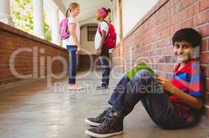 Schoolboy with friends in background at school corridor