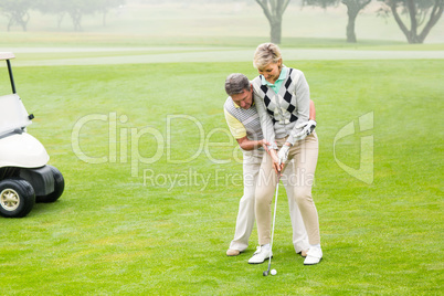 Golfing couple putting ball together Golfing couple putting ball together