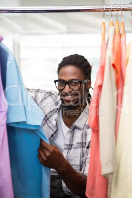 Male fashion designer looking at rack of clothes