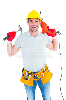 Smiling handyman holding hammer and drill machine