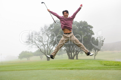 Excited golfer jumping up and smiling at camera