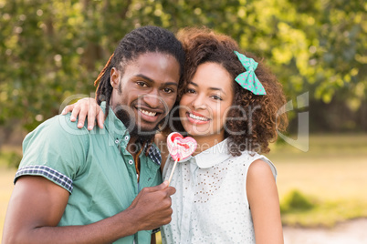 Cute couple in the park sharing a lollipop