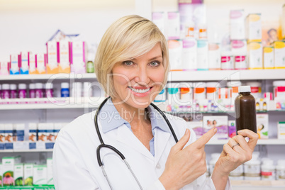 Smiling doctor pointing a drug bottle