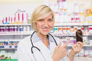 Smiling doctor pointing a drug bottle