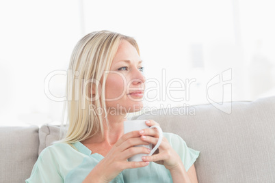 Woman holding coffee cup while looking away