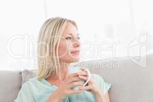 Woman holding coffee cup while looking away