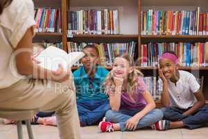 Cute pupils and teacher having class in library