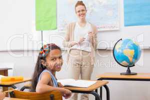 Cute pupil and teacher in classroom with globe