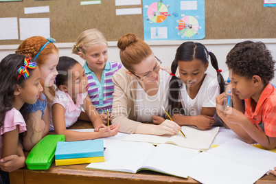 Teacher and pupils working at desk together