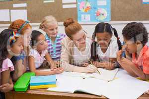 Teacher and pupils working at desk together