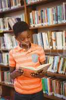 Cute boy reading book in library