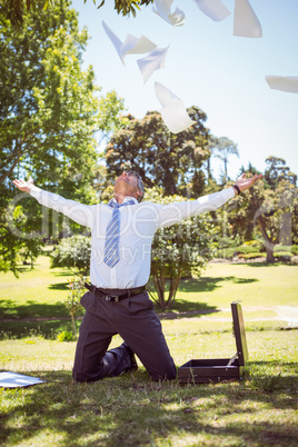 Businessman tossing papers in the park