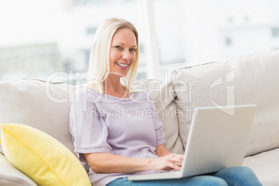 Smiling woman on sofa using laptop in living room