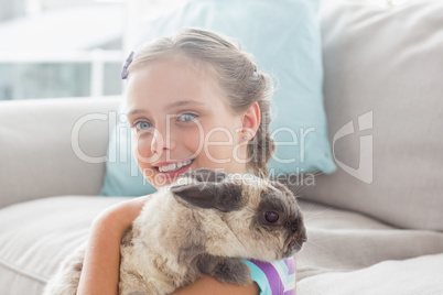 Happy girl holding rabbit in living room