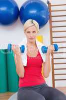 Blonde woman lifting dumbbells on exercise ball
