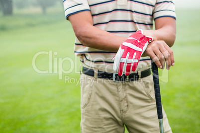 Golfer standing and leaning on his club