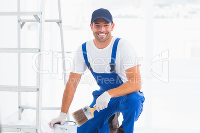 Handyman with paintbrush and can at home