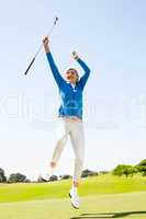 Female golfer leaping and cheering