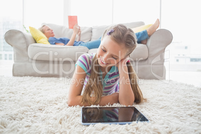 Happy girl using digital tablet on rug in living room