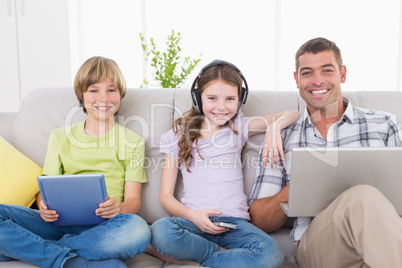 Happy man with children using technologies on sofa