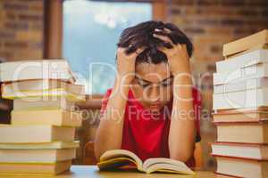Tensed boy sitting with stack of books