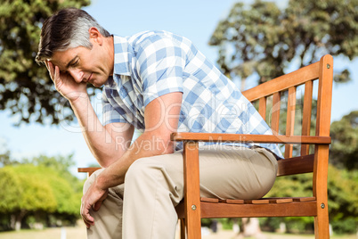 Upset man sitting on park bench