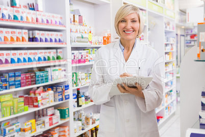 Smiling pharmacist writing on clipboard