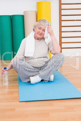 Tired senior woman on exercise mat