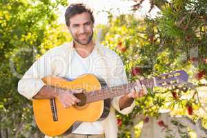 Happy man smiling at camera playing guitar