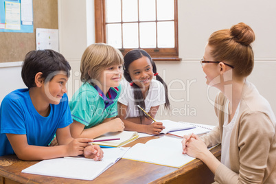 Teacher and pupils working at desk together