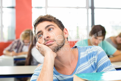 Thoughtful student with books in classroom