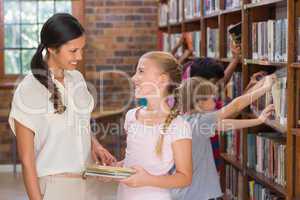 Cute pupils and teacher looking for books in library