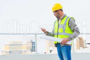 Architect with blueprints reading clipboard outdoors