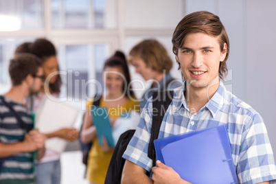 Male student holding folder in college