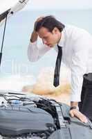 Stressed businessman looking at engine