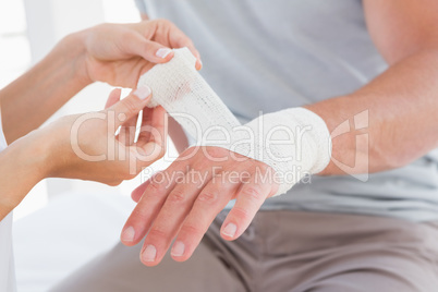 Doctor bandaging her patient hand