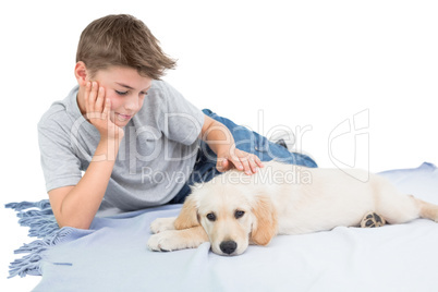 Boy stroking dog while lying on blanket
