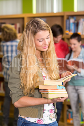 Female college student holding books in library