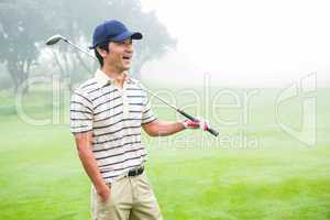 Smiling golfer standing and holding his club