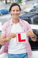 Learner driver smiling and holding l plate