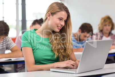 Female student using laptop in classroom