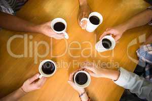 Hands holding coffee mugs on table