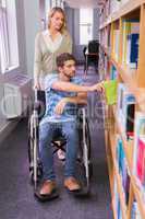 Smiling disabled student with classmate in library