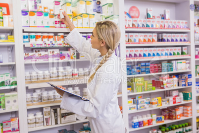 Junior pharmacist taking medicine from shelf