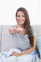 Young woman changing channels on sofa