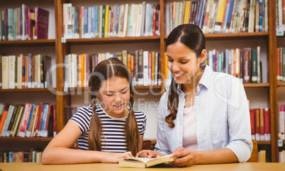 Teacher and girl reading book in library