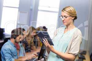 Teacher using digital tablet in computer class